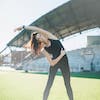 Женщина делает упражнения на площадке стадиона